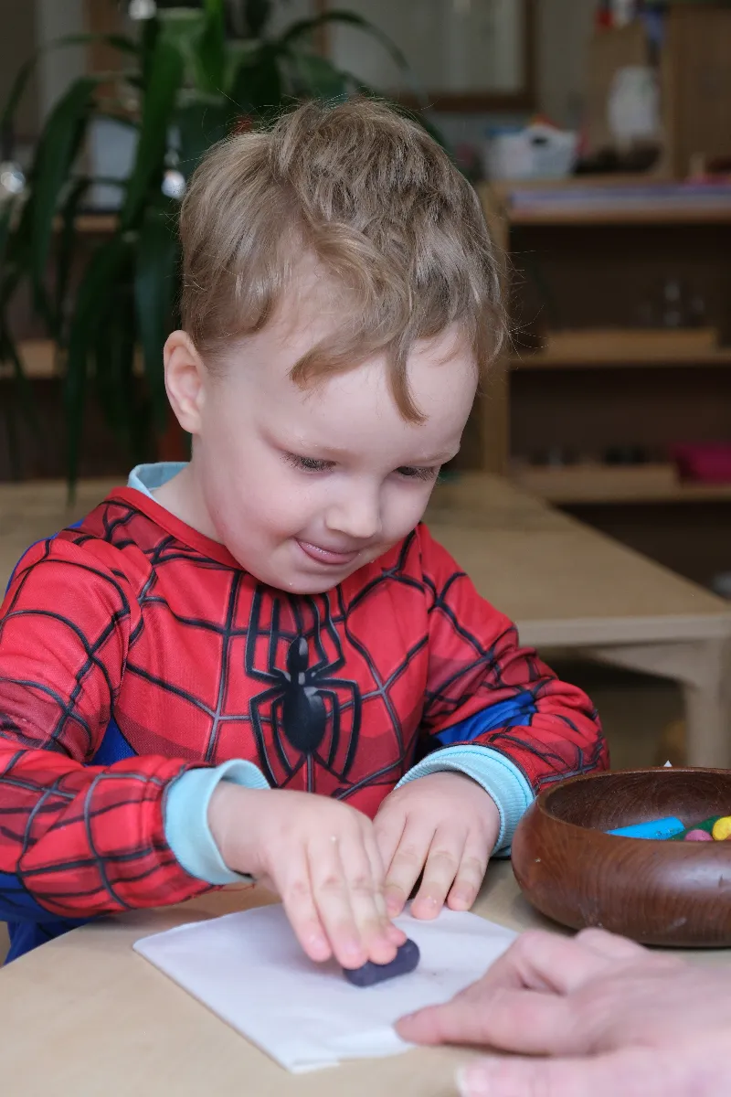 child in spikerman top doing some drawing